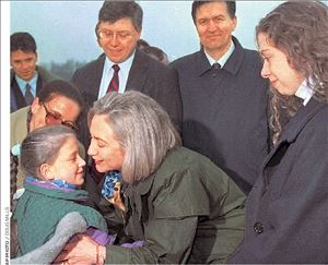 «Μπήκαμε  τρέχοντας   στα αυτοκίνητα», διηγήθηκε η Χίλαρι Κλίντον. Η φωτογραφία όμως από την  άφιξή της  στην Τούζλα  της Βοσνίας  το 1996 δεν  δείχνει καμία βιασύνη.  Η τότε πρώτη κυρία φιλά ήρεμη το  κοριτσάκι  που της έδωσε ανθοδέσμη και της  απήγγειλε  ποίημα   